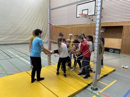 Die Klasse 5a löst beim Erlebnispädagogischen Tag unter der Anleitung von Frau Meid eine knifflige Teamaufgabe.